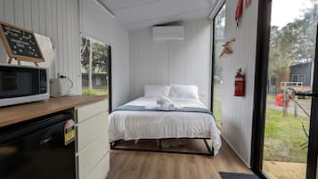 A bedroom with a bed, a microwave, and a small kitchenette.
