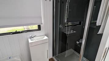 A compact bathroom with a shower, toilet, and sink.