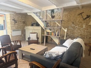 A living room with a sofa, chairs, a coffee table, a bookshelf, and a staircase.