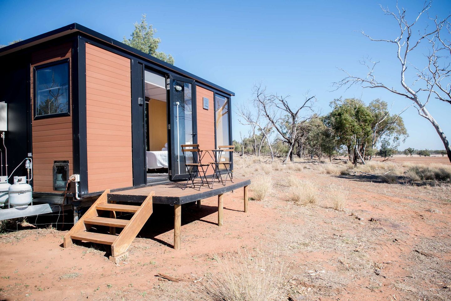 Un bâtiment moderne, de plain-pied, doté d’une terrasse en bois et d’une grande porte coulissante.