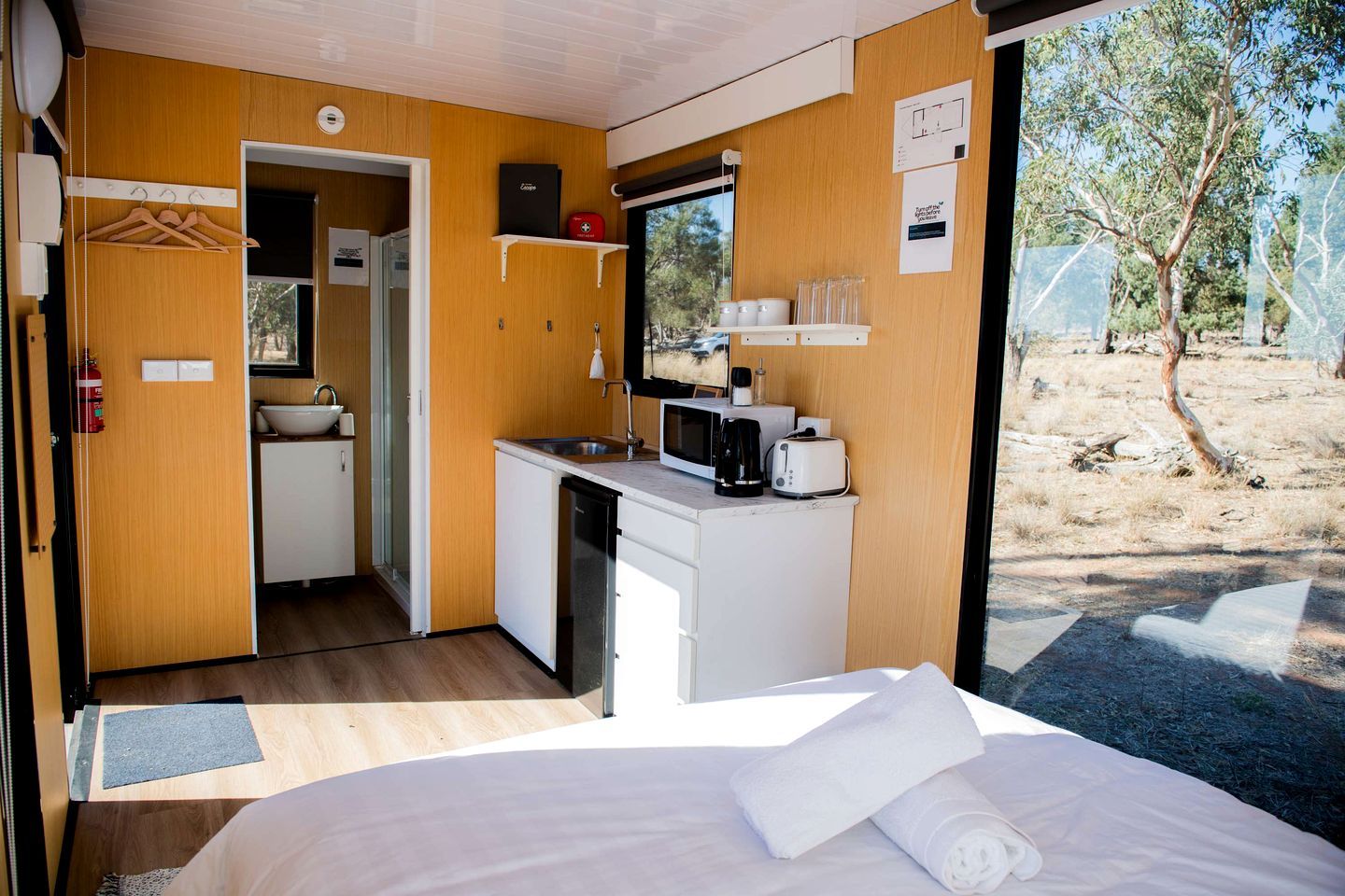 Una habitación compacta con cama, kitchenette y vistas al exterior.