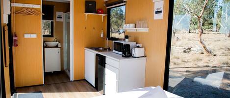 Una habitación compacta con cama, kitchenette y vistas al exterior.