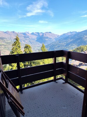 A balcony with a metal floor, wooden railing, and a view of mountains and trees. - Apartment in Les Coches with a View of Mont Blanc (La Plagne Tarentaise)