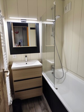 A bathroom with a white sink, wooden vanity, a mirror, a glass shower enclosure, and a bathtub. - Apartment in Les Coches with a View of Mont Blanc (La Plagne Tarentaise)