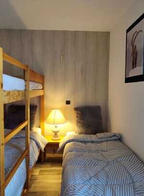 Une chambre avec des lits superposés, une lampe de chevet et un tableau encadré au mur.