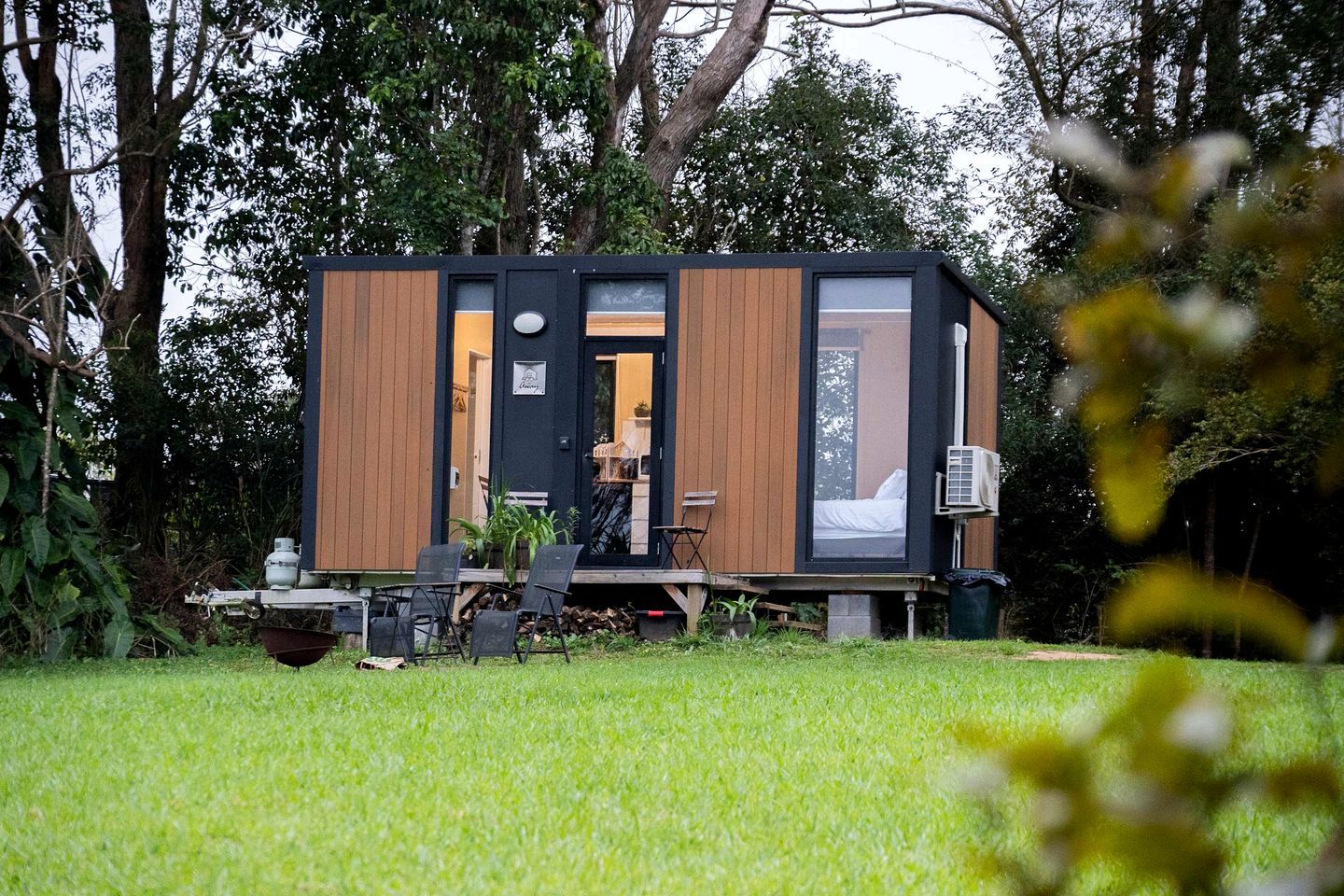 Una cabaña moderna con terraza, comedor y habitación visible.