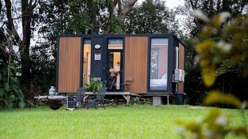 Una cabaña moderna con terraza, comedor y habitación visible.