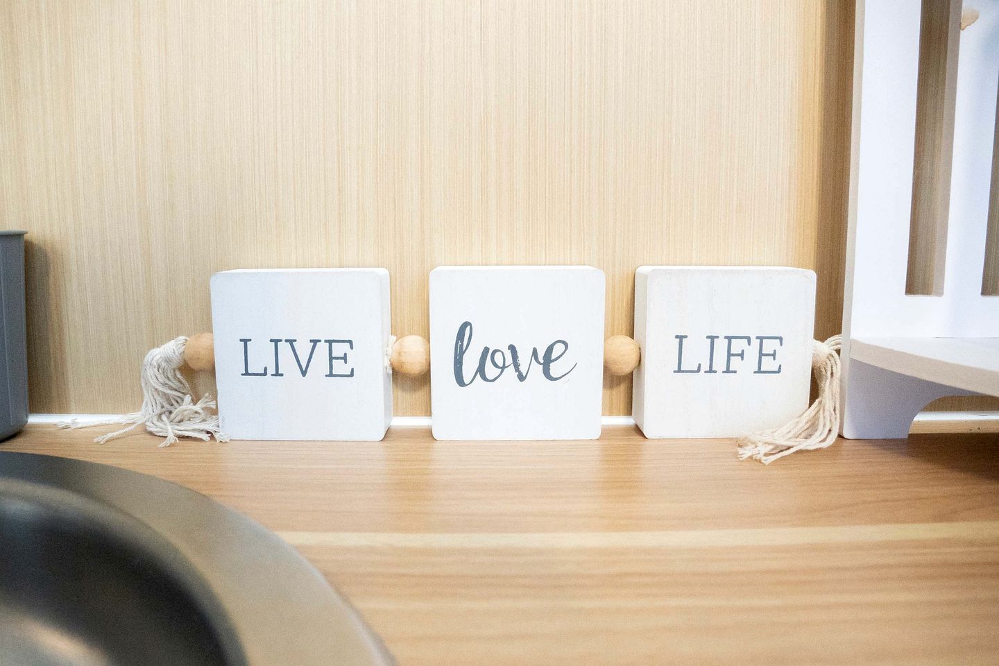 Three wooden blocks with the words 'LIVE,' 'love,' and 'LIFE' on a wooden shelf.
