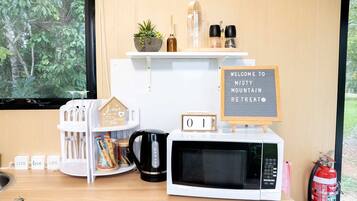 A kitchen area with a microwave, a coffee maker, a calendar, and a welcome sign.