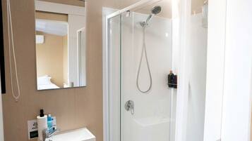 Une salle de bain moderne avec une douche à parois de verre, un lavabo blanc et un miroir.
