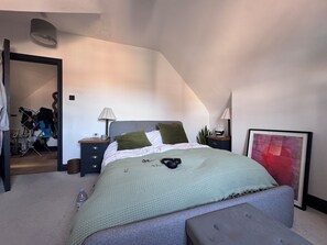 A bedroom with a bed, bedside tables, a lamp, a framed picture, and a door leading to another room. - Enchanting Loft Hideaway near Honor Oak Park (London)