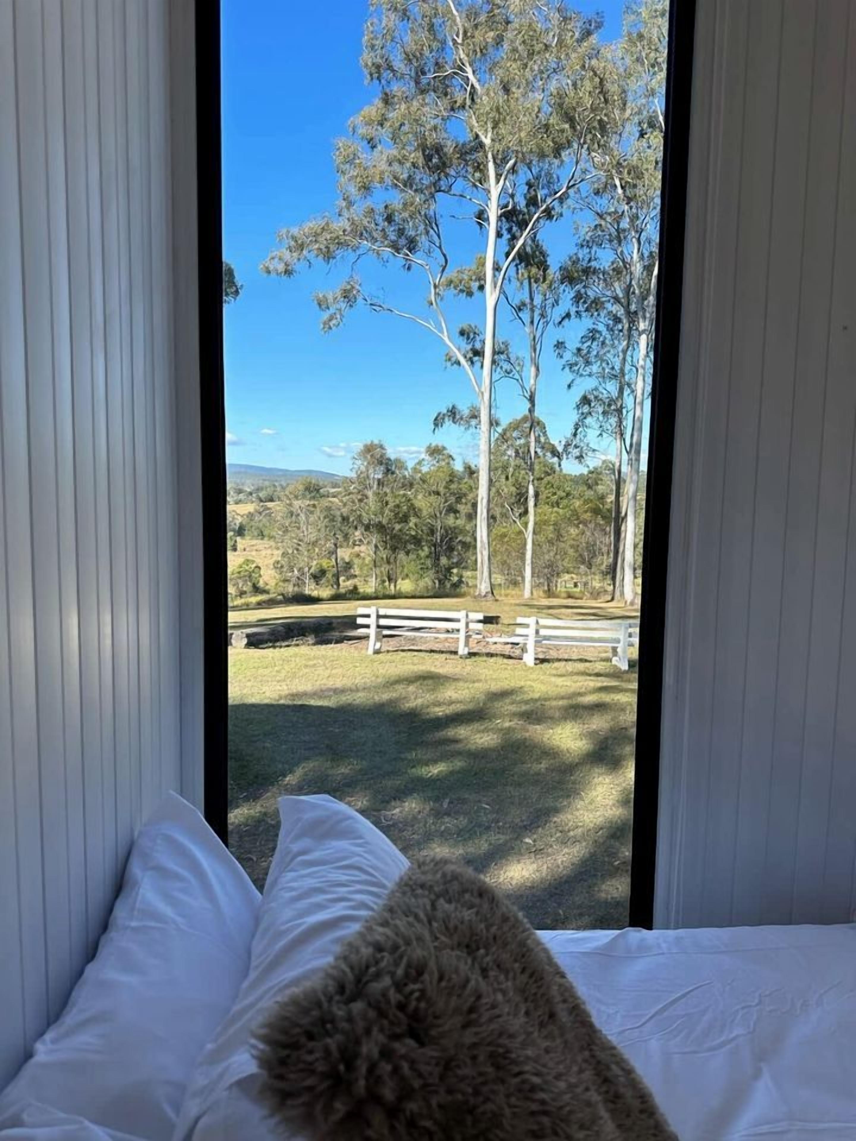 Una stanza con un letto e vista su una zona erbosa con alberi e una recinzione.