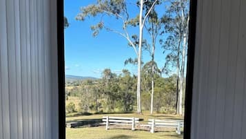 Una stanza con un letto e vista su una zona erbosa con alberi e una recinzione.