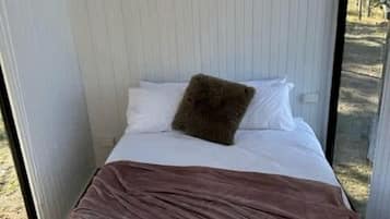 Een kleine kamer met een bed, een raam en een airconditioning.