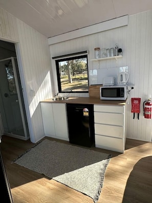 A compact kitchen with a microwave, coffee maker, and a fire extinguisher.