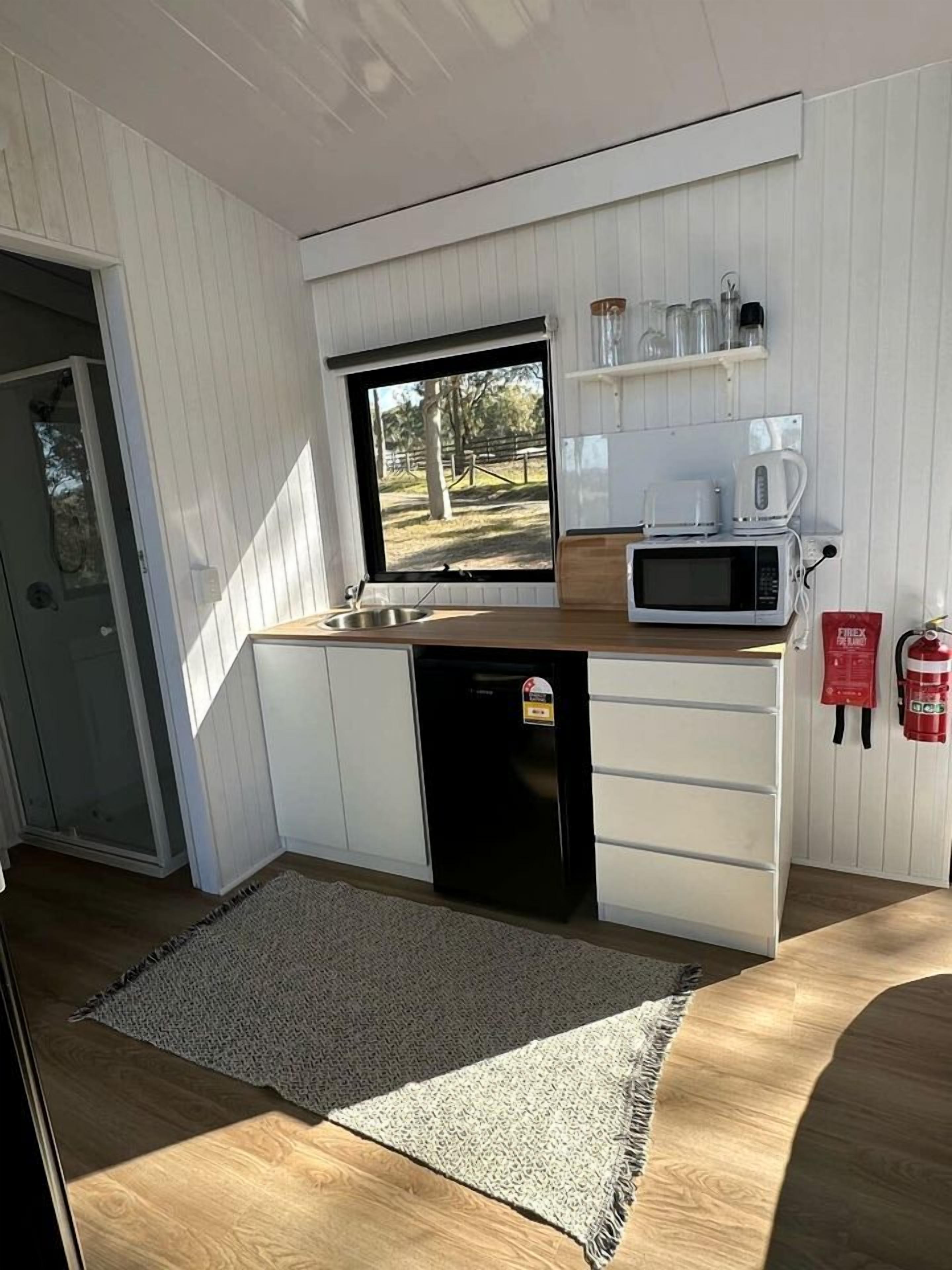 Una cocina compacta equipada con microondas, cafetera y extintor.