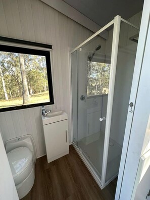 A compact bathroom with a toilet, sink, and shower.