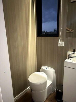Ein kleines Badezimmer mit Toilette, Waschtisch und Fenster.