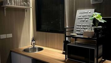 Una cocina moderna con un lavamanos, una cafetera y un cartel de bienvenida.