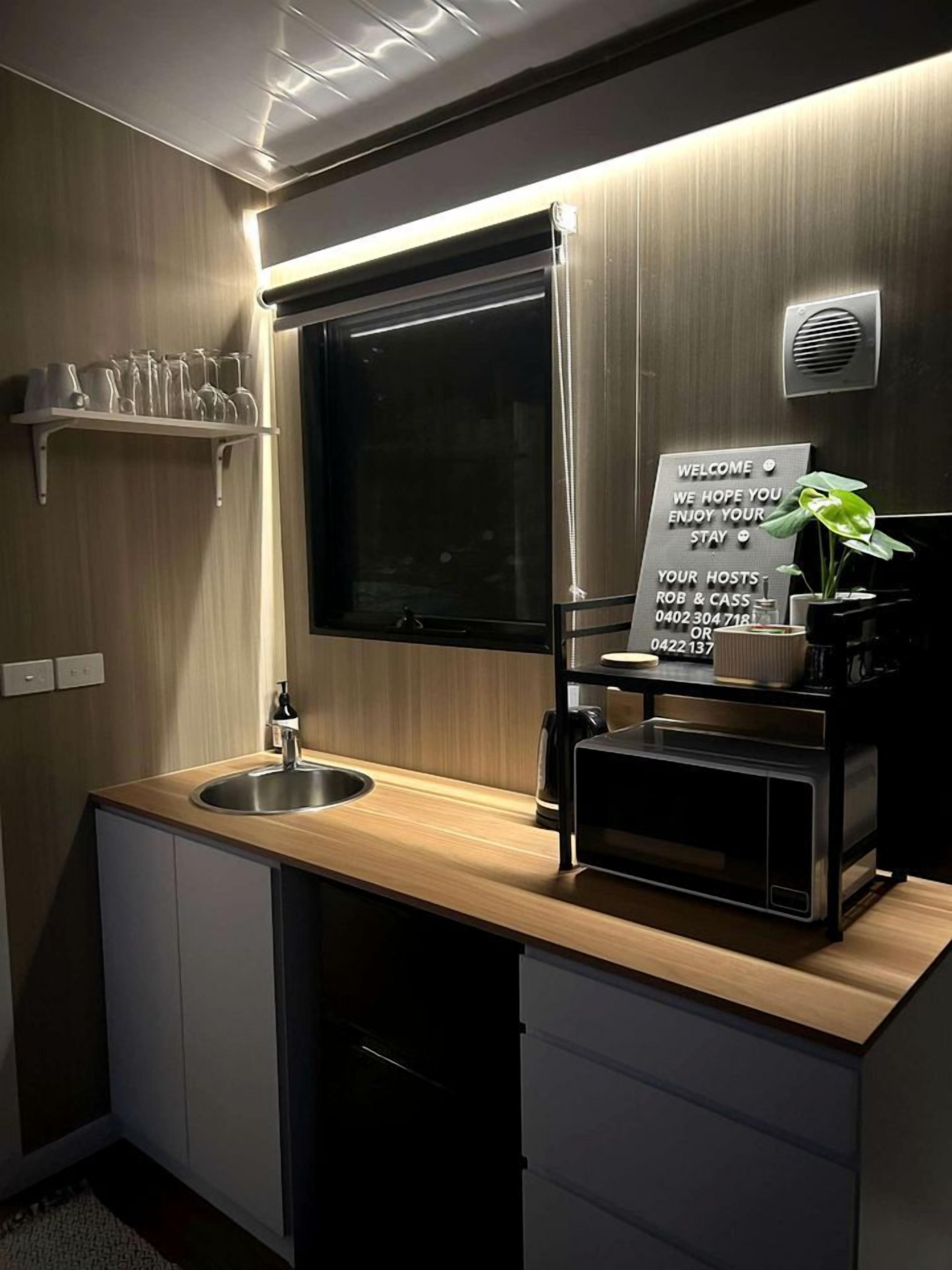 A modern kitchen with a sink, a coffee machine, and a welcome sign.