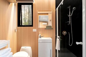 A compact bathroom with a toilet, sink, and shower. - Springwater Gardens Tiny Home Rental for a Yarra Valley Holiday (Toolangi)