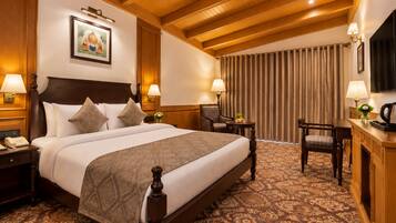 A hotel room with a large bed, a desk, a chair, a television, and a painting on the wall.