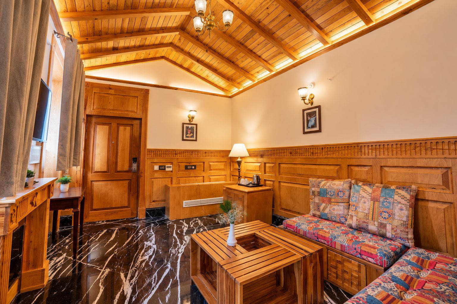Un intérieur en bois avec un comptoir d’accueil, un canapé agrémenté de coussins à motifs et un sol en marbre.