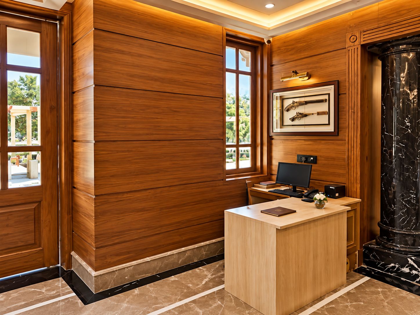 A reception desk with a computer, a framed picture on the wall, and a large window.