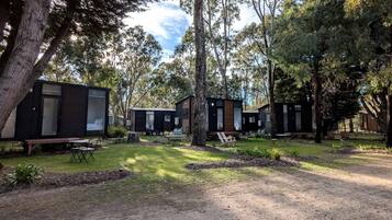 A campsite with multiple cabins, outdoor seating, and a grassy area.