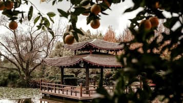 Ein traditioneller Pavillon mit Ziegeldach, umgeben von Wasser und Bäumen.
