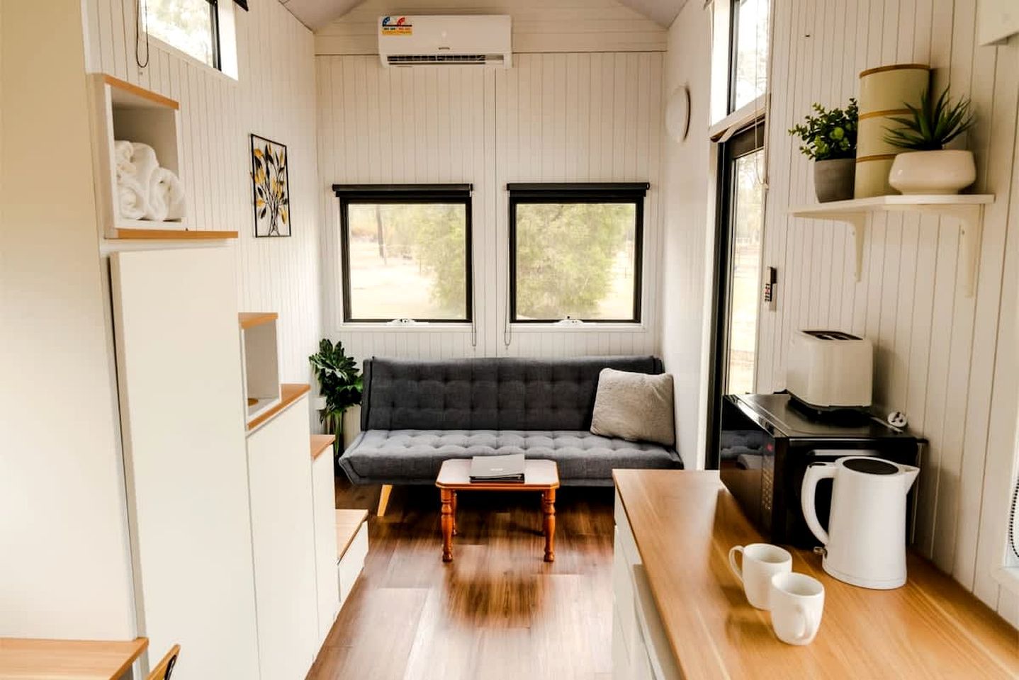 Un espace de vie compact comprenant un canapé, une table basse, un coin cuisine et une fenêtre.