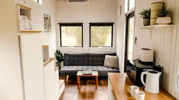 Un espace de vie compact comprenant un canapé, une table basse, un coin cuisine et une fenêtre.