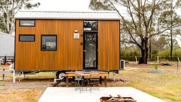 Une petite construction en bois d’un seul étage, dotée d’une porte coulissante, d’un petit porche et d’un dallage en béton à l’avant.