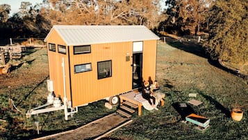 Eine kleine Holzhütte mit einem Metalldach, einer Veranda und einer kleinen Terrasse.