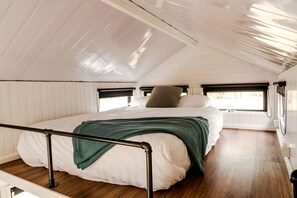 A bedroom with a bed, a window, and a wooden floor.