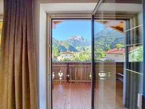 Une pièce dotée d’une porte-fenêtre coulissante donnant sur un balcon avec un plancher en bois et une vue sur une chaîne de montagnes.