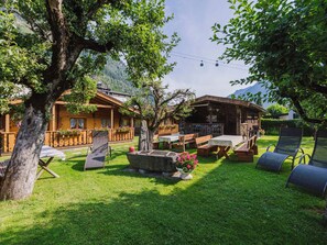 Una cabaña de madera con zona de patio, mobiliario exterior y vistas a las montañas.