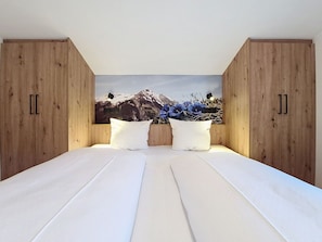 Ein Schlafzimmer mit einem Bett, einem Holzschrank und einer Wandmalerei mit Berglandschaft.