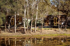 A cabin with a wooden deck, surrounded by trees and a body of water.