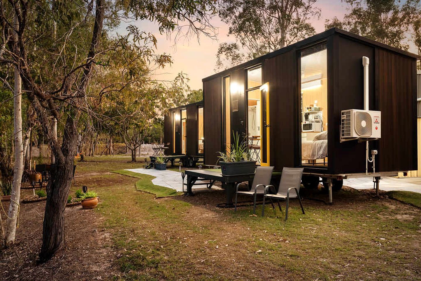Una casa móvil moderna y compacta con ventanas amplias, comedor y terraza.