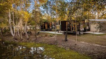 Ein Campingplatz mit Holzhütten, einem kleinen Teich und Bäumen.