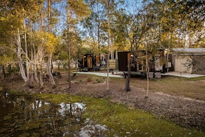 A campsite with cabins, a small pond, and trees.