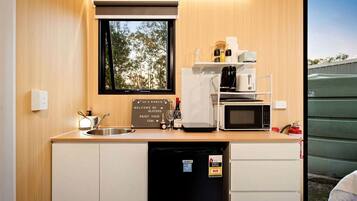 A compact kitchenette with a sink, a coffee maker, a microwave, and a small refrigerator.