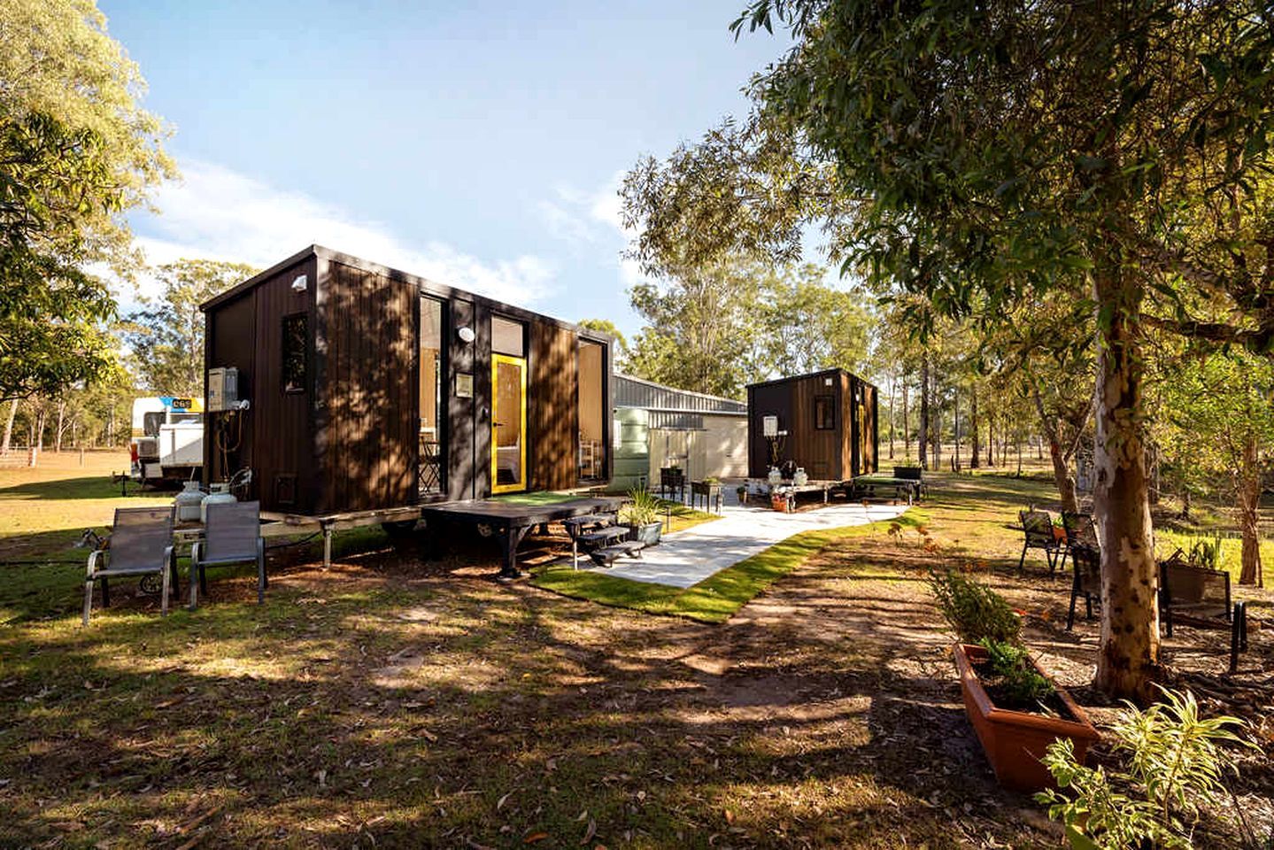 A modern RV-style building with a covered outdoor area, a picnic table, and a small deck.