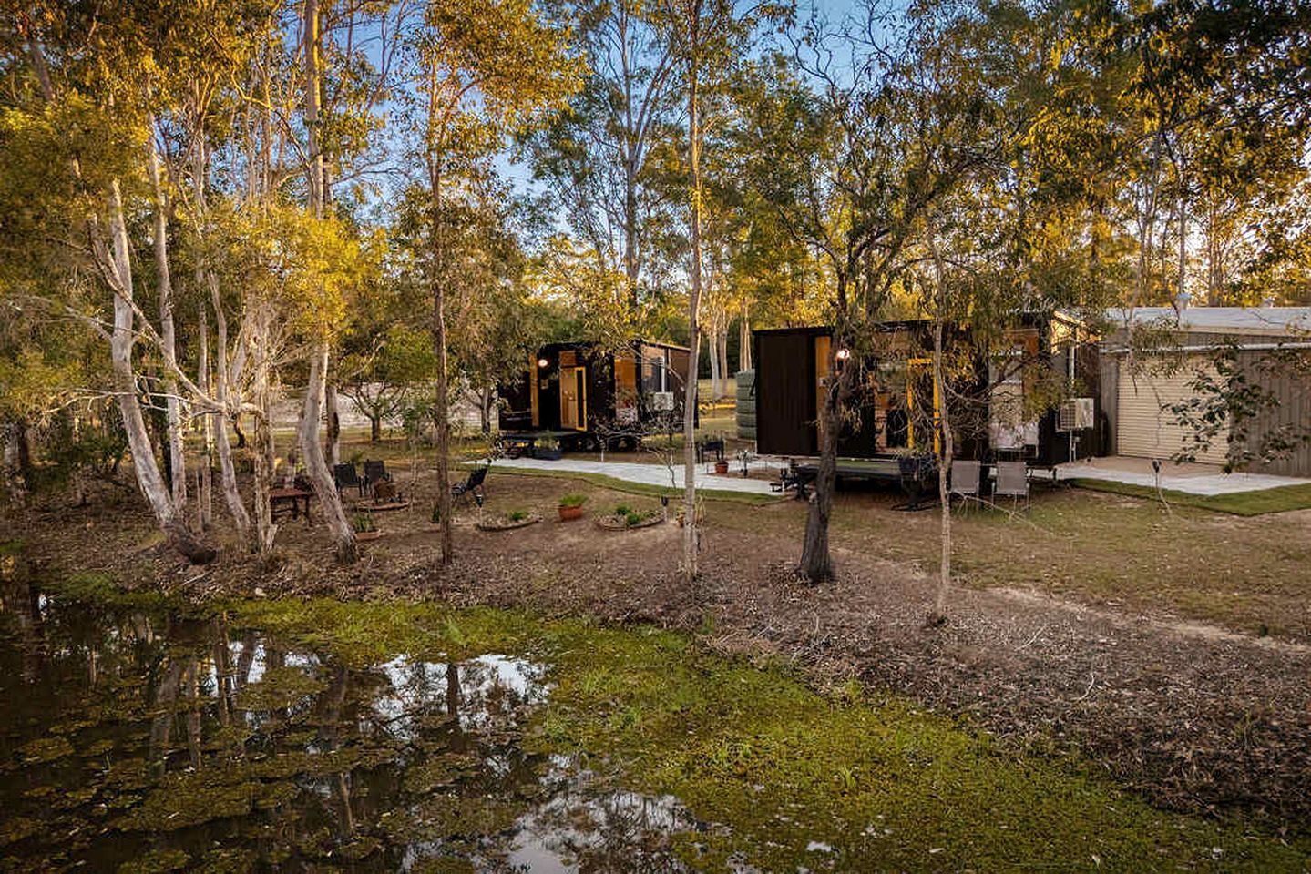 A campsite with cabins, a small pond, and trees.