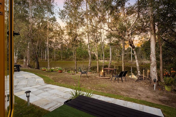 A backyard with a fire pit, seating area, and a pond.