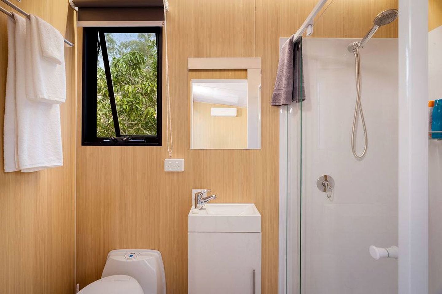 A compact bathroom with a window, a shower, and a toilet.