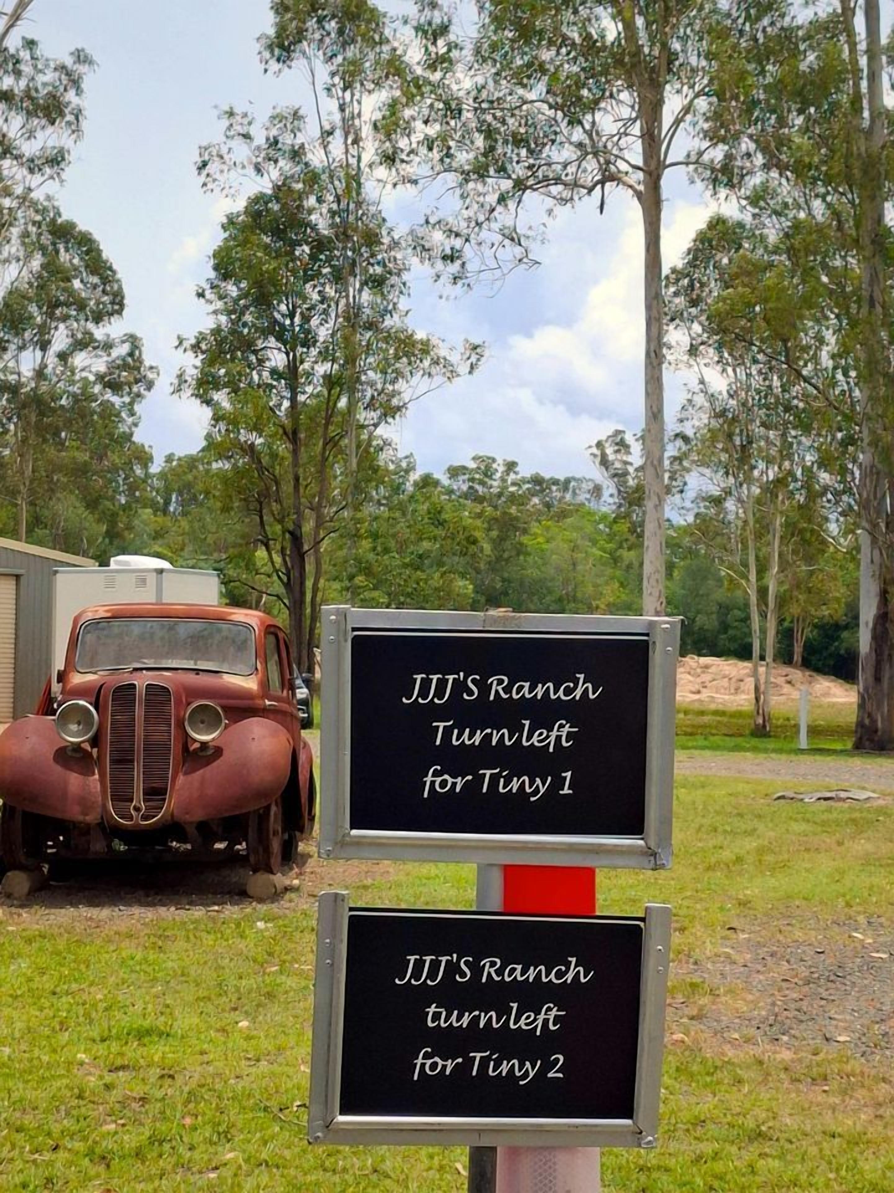 A vintage car and two directional signs indicating 'JJJ's Ranch Turn Left for Tiny 1' and 'JJJ's Ranch Turn Left for Tiny 2'.