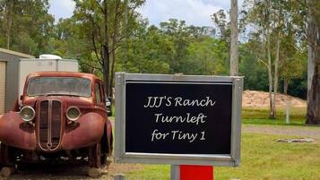 A vintage car and two directional signs indicating 'JJJ's Ranch Turn Left for Tiny 1' and 'JJJ's Ranch Turn Left for Tiny 2'.