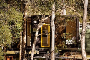 A train car with a yellow door, surrounded by trees.